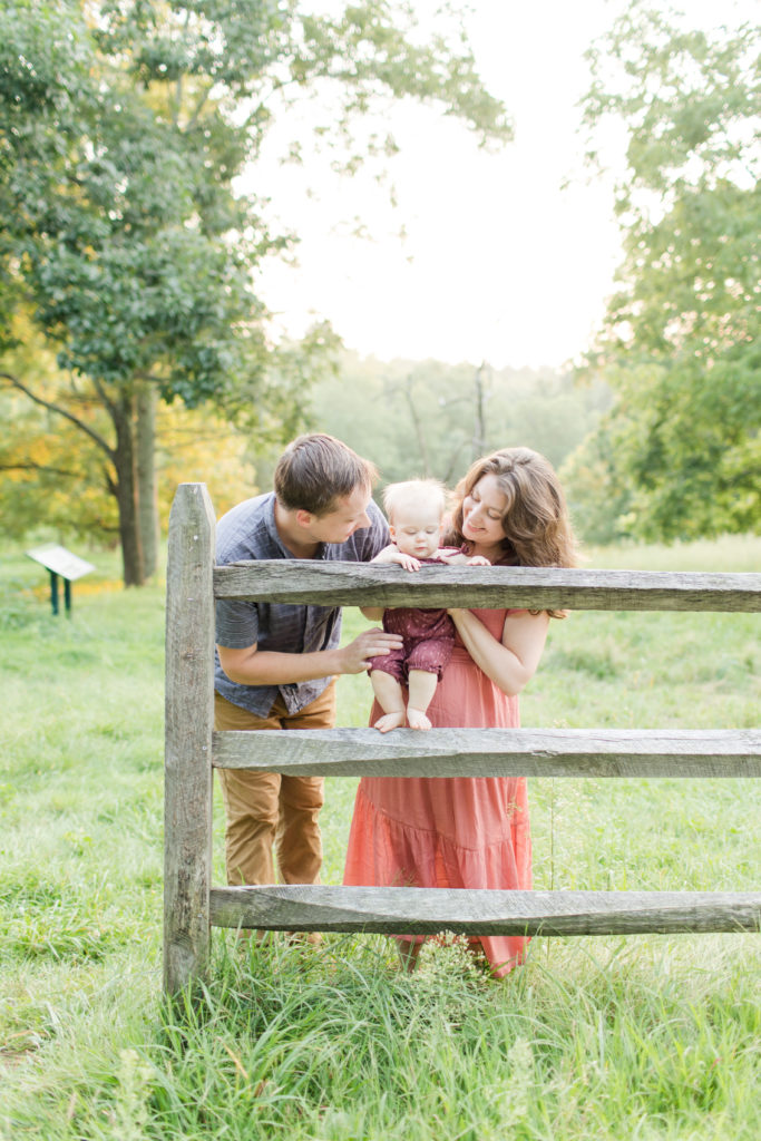 Young family holding up their baby girl during natural light photo session in the summer in Sherborn, Massachusetts