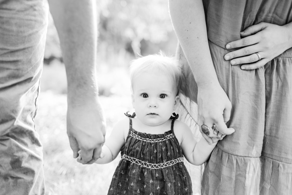 Metrowest Boston Family Photographer - Black and white photo of young baby standing with parents. Family photos in Sherborn, Massachusetts with Corinne Isabelle Photography