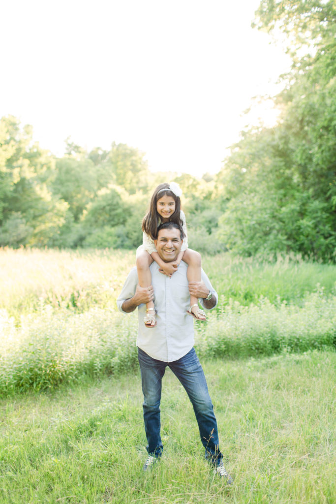 Holliston Family Photographer - Father with young daughter on his shoulders, smiling for family photo session in Sherborn, Massachusetts.