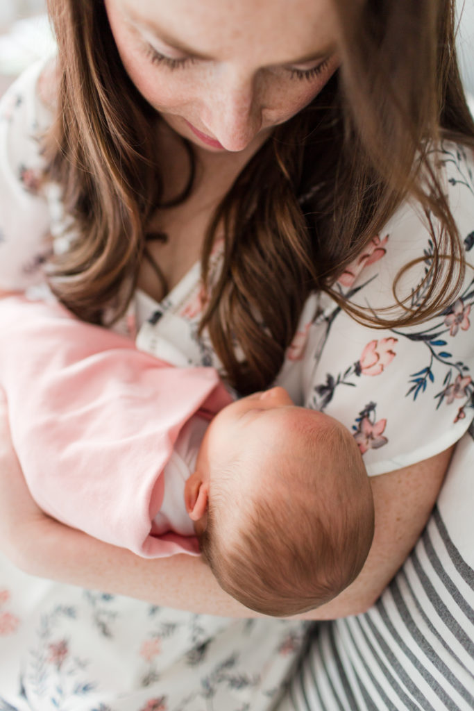 Mom holding her newborn baby girl in natural light during newborn session.