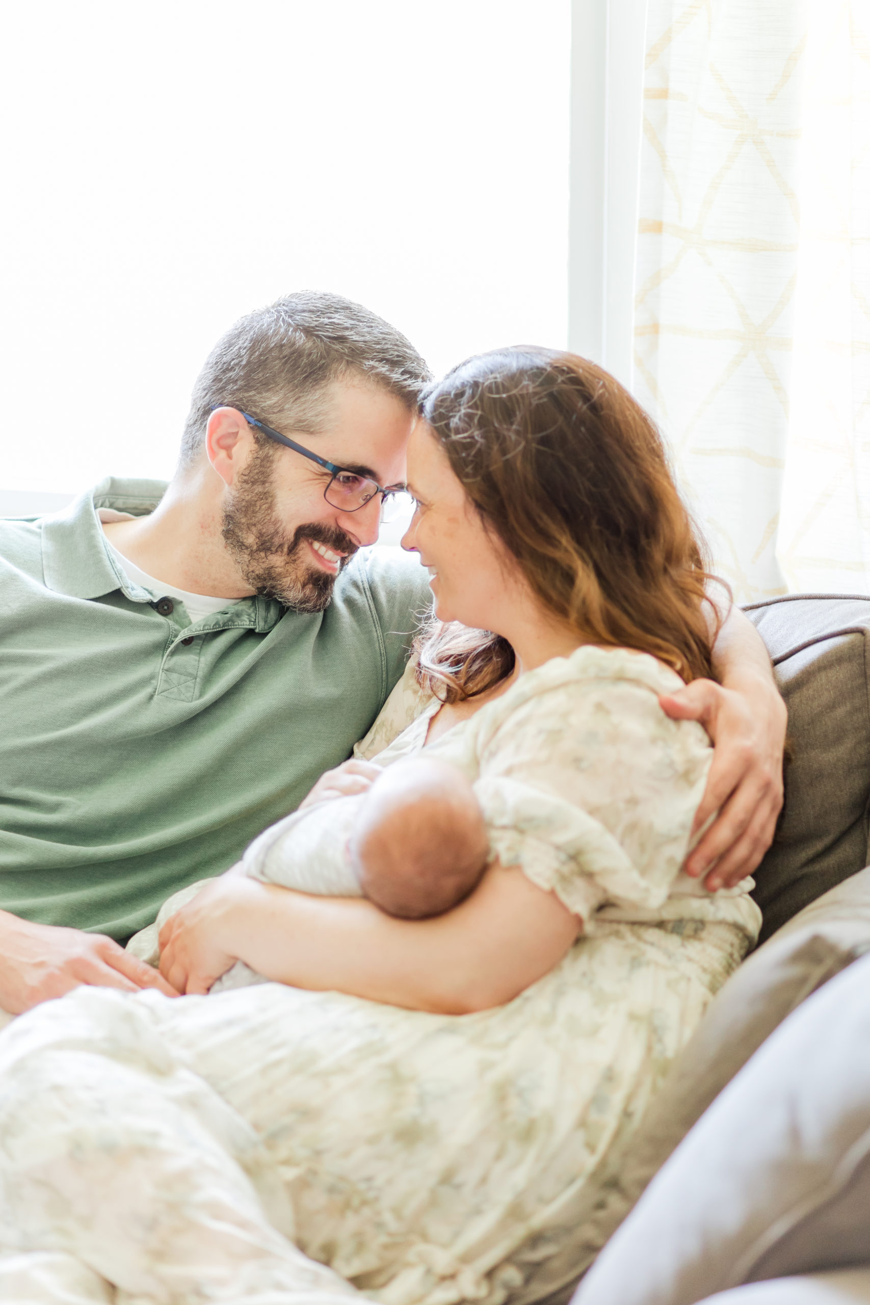 Newborn baby being held by their mother and father while snuggling during photo session with Holliston Newborn Photographer Corinne Isabelle