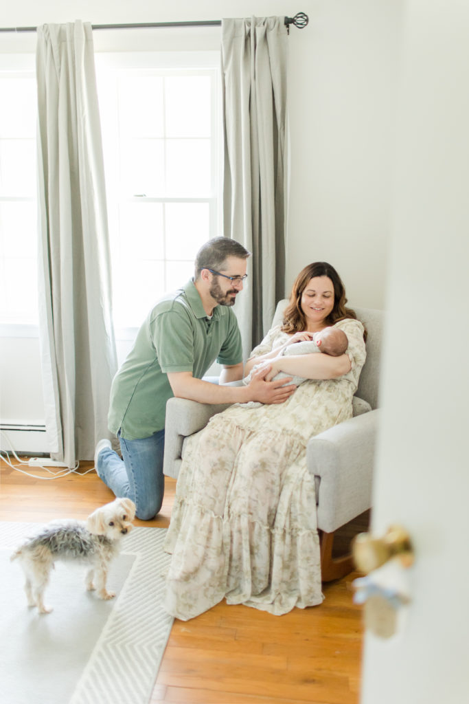 Newborn baby being held by their mother with father with Holliston Newborn Photographer Corinne Isabelle