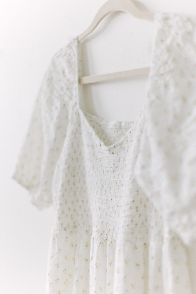 Close up of white dress with floral accents offered by Boston baby photographer Corinne Isabelle