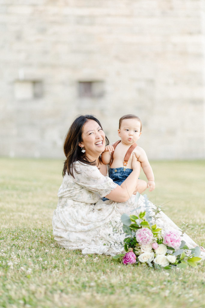 Young mom laughing while holding her son during their 1 year old Boston baby photography session at Castle Island