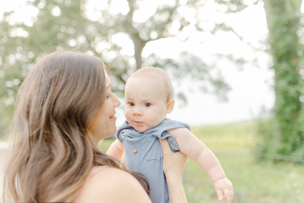 Young mom holding her baby boy outdoors during a lifestyle family session with Boston Family Photographer Corinne Isabelle