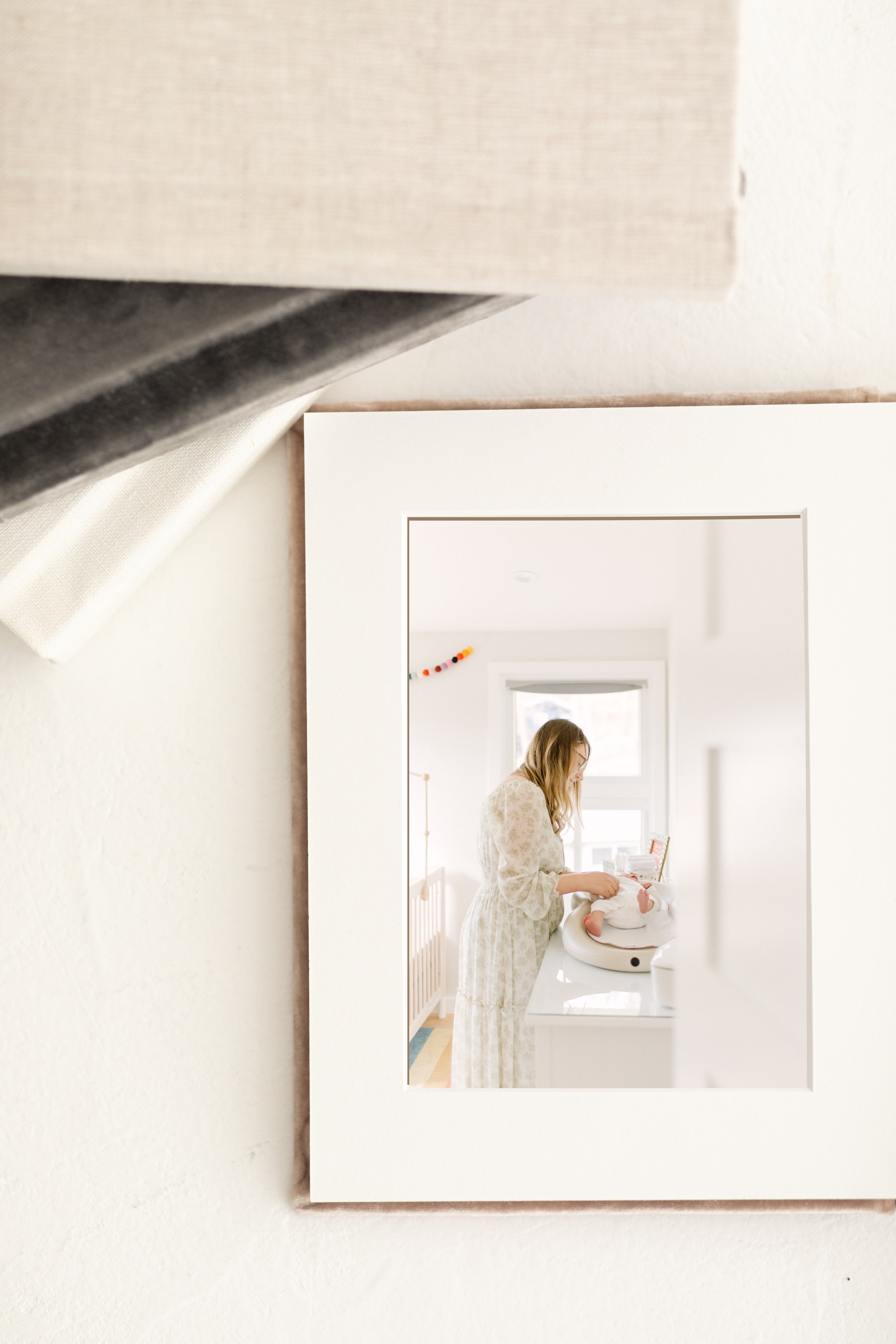 Photo of a printed image of a young mother changing her newborn baby's diaper during Boston family photography session with Corinne Isabelle