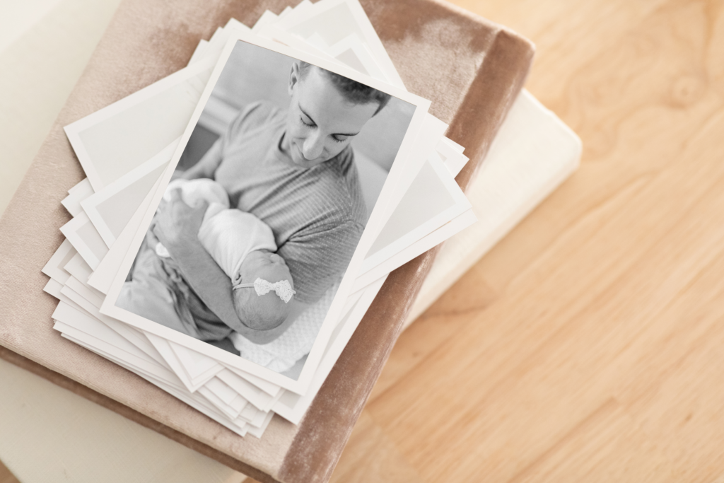 Photo of printed photos taken of a young father holding his newborn baby during Boston family photography session with Corinne Isabelle