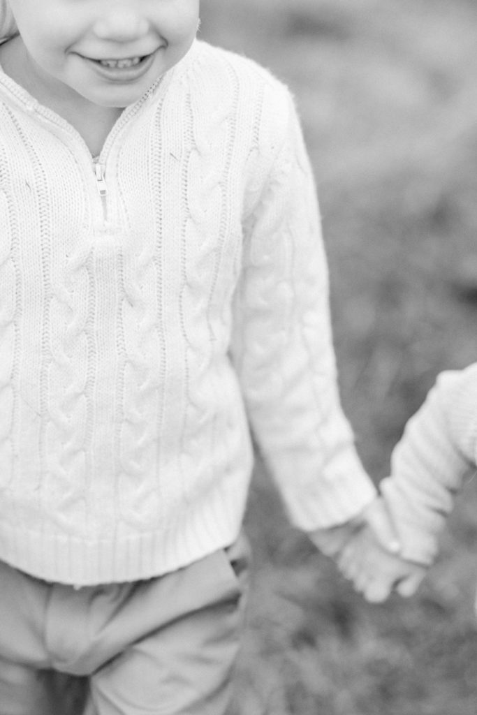 Young toddler boy holding his sister's hand during Boston family photography session with Corinne Isabelle