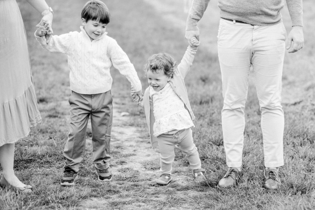 Young family holding hands during photo session with Corinne Isabelle who specializes in Boston Family Photography.