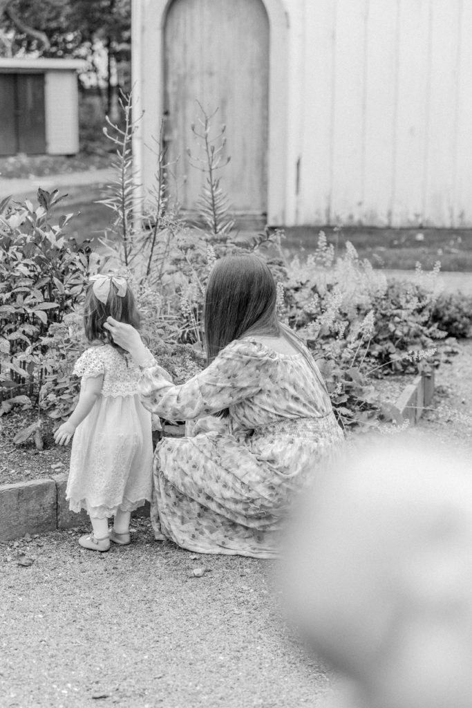 Mom crouching down to daughter during outdoor spring photo shoot with Boston Motherhood Photographer Corinne Isabelle Photography