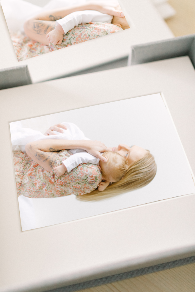 Photo of printed photos taken of a young mother holding her newborn baby during session with Corinne Isabelle who specializes in Boston Family Photography.