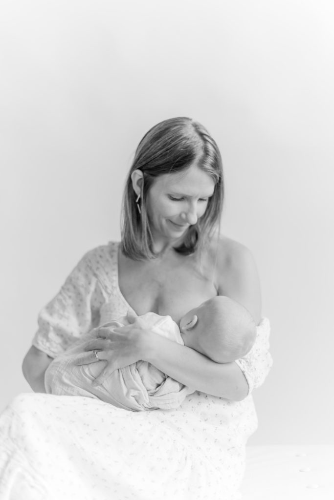 Black & white photo of young mom breastfeeding her newborn baby during motherhood photo session with Boston Newborn Photographer Corinne Isabelle