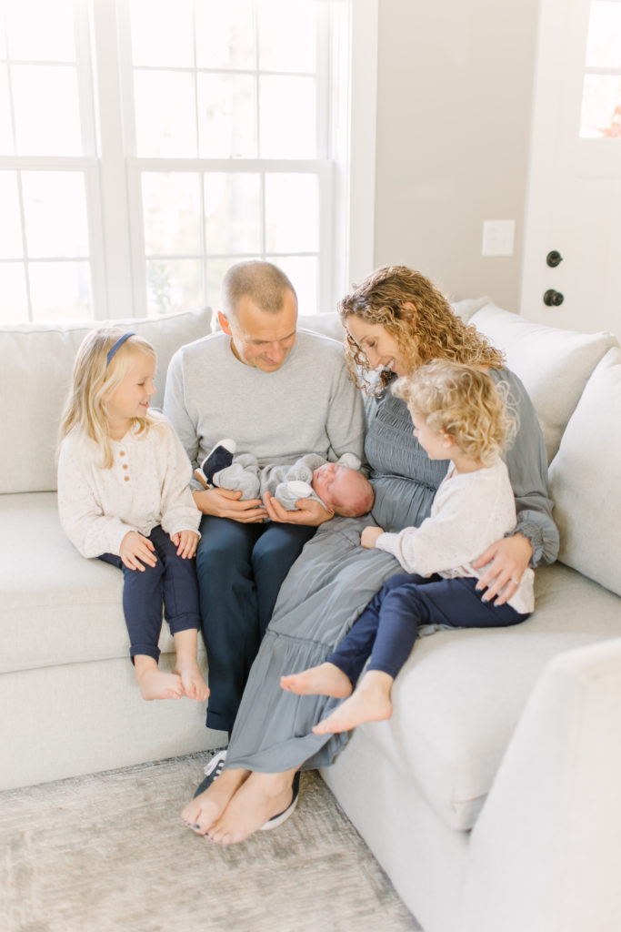 Young family holding their newborn baby during in-home photo session with Natick newborn photographer, Corinne Isabelle