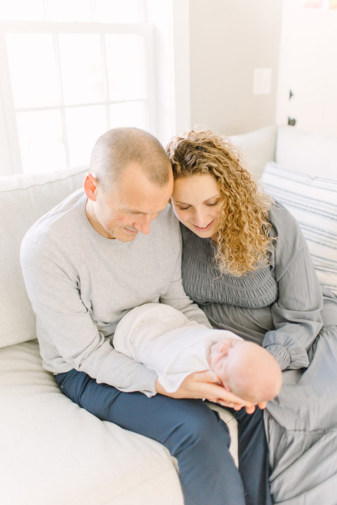 Young family holding their newborn baby during in-home photo session with Natick newborn photographer, Corinne Isabelle