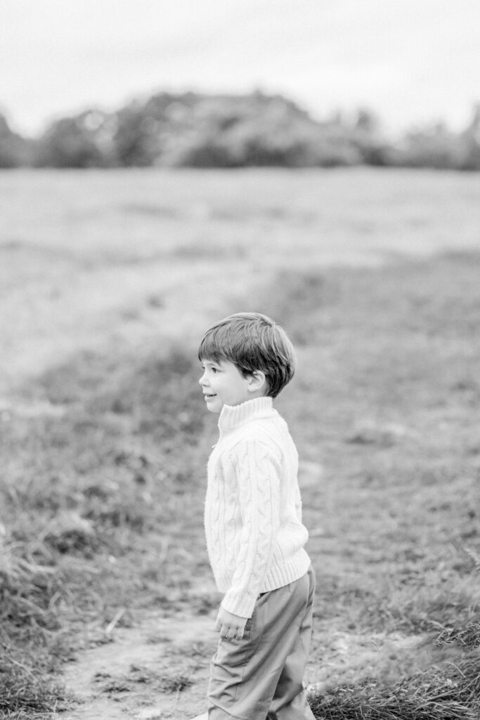 Toddler boy staring to the side in an open field during photo session.