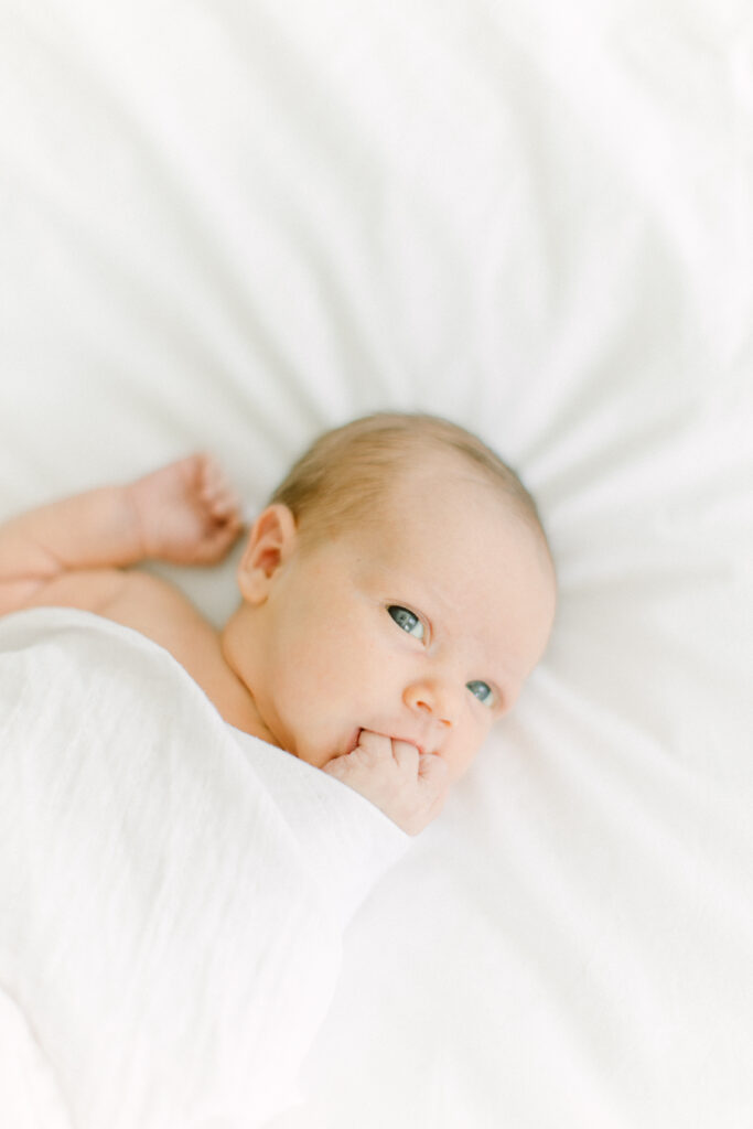 Newborn baby awake and resting on bed during photo session with Boston Area Newborn Photographer Corinne Isabelle