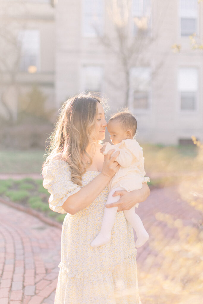 Young mom holding her baby in the sunlight during boston area family photography session.