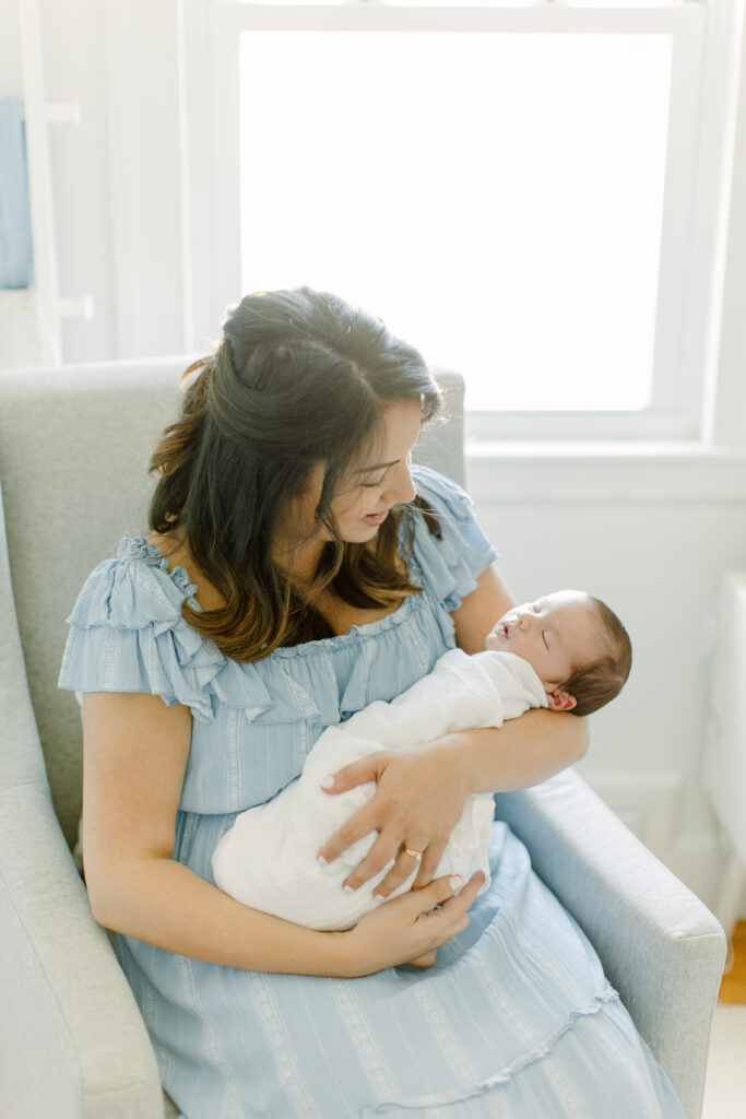 New mom holding her baby boy during in-home newborn photo session with Boston newborn photographer Corinne Isabelle