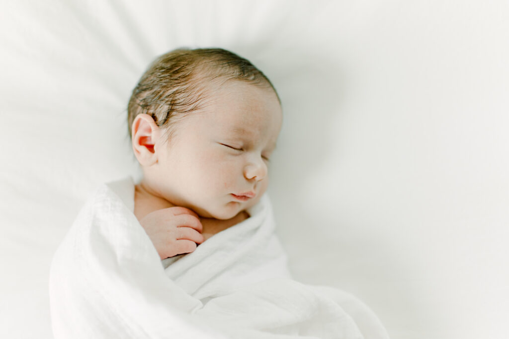 baby boy sleeping on bed during in-home photo session with Boston newborn photographer Corinne Isabelle